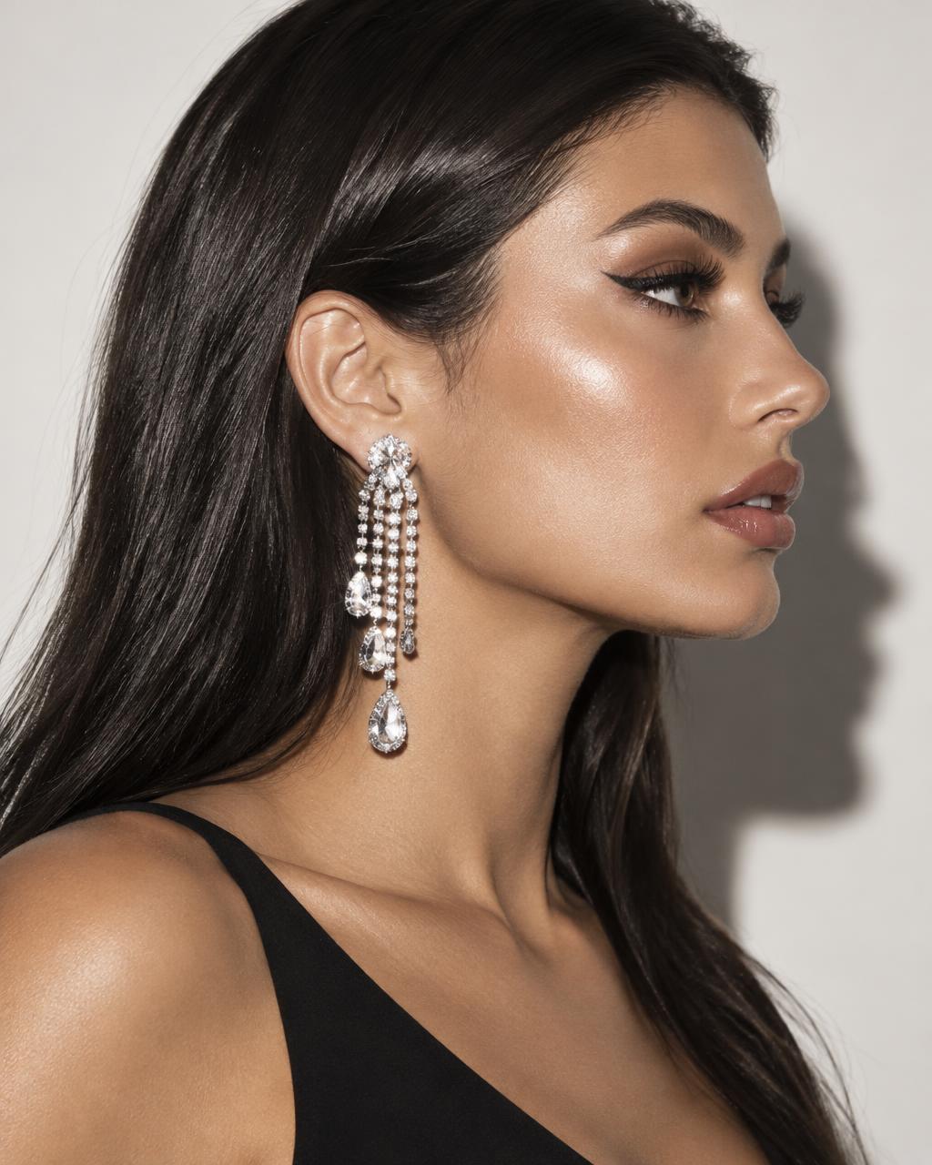 Profile of a model with long dark hair wearing long silver rhinestone chandelier earrings