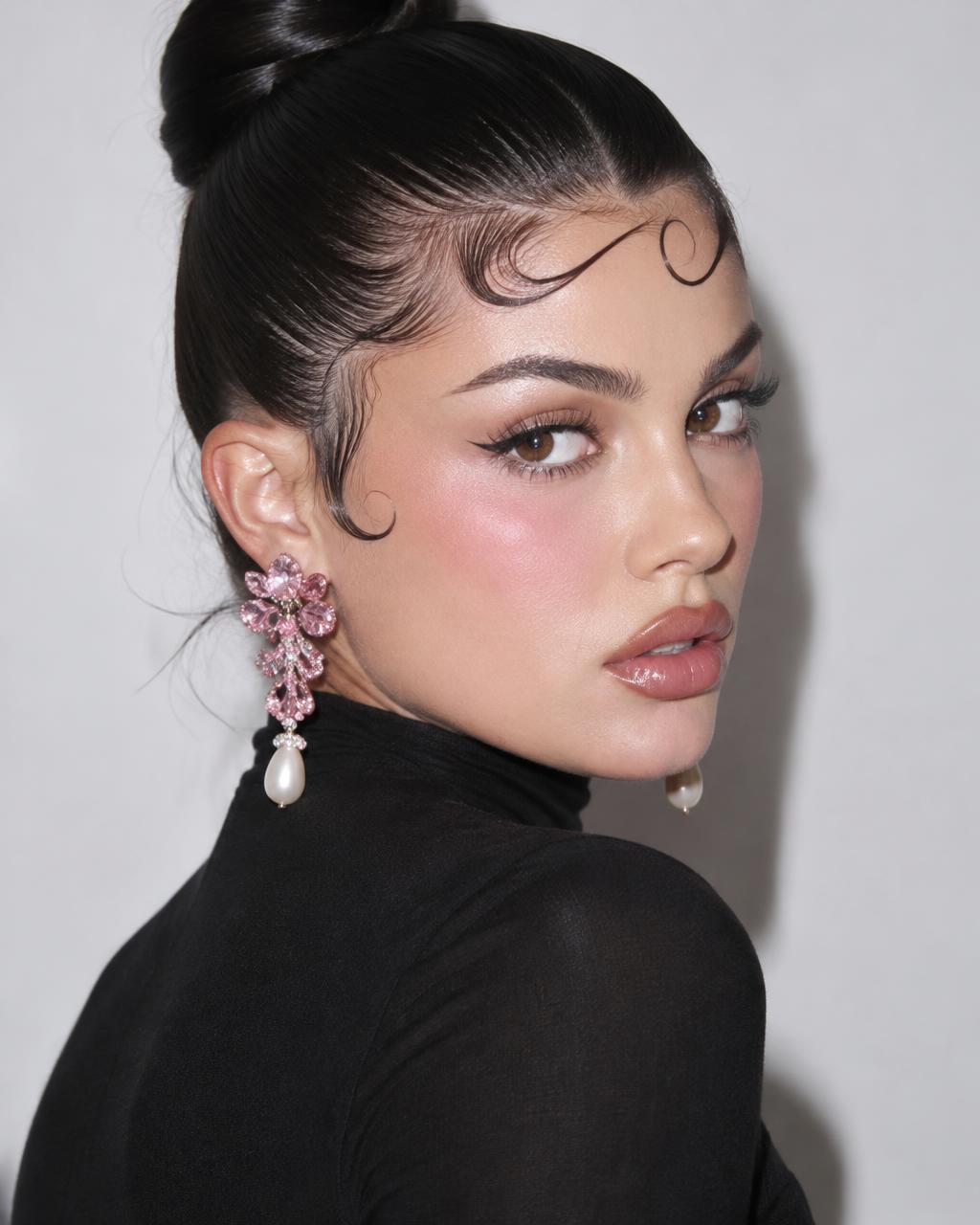 Model with a sleek bun and sculpted baby hair wearing pink crystal and pearl drop earrings