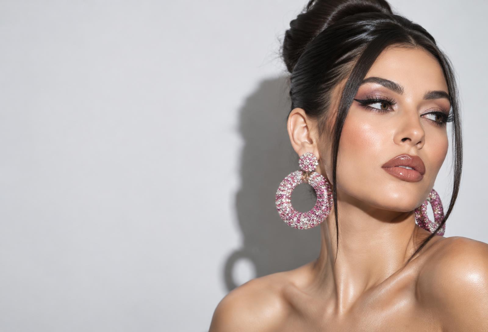 Model with a sleek dark updo, winged eyeliner and oversized pink crystal hoop earrings